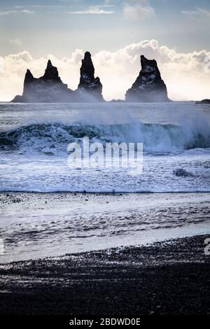 Waves crash on the beach in front of Reynisdrangar basalt sea stacks in winter at Vík í Mýrdal on Iceland's South coast Stock Photo