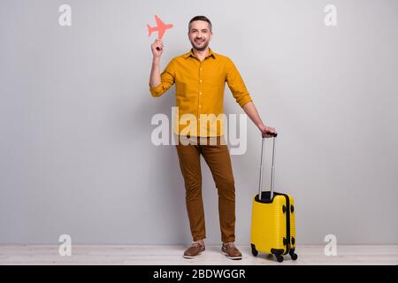 Full length photo of positive cheerful man ready travel departure weekend hold big suitcase red paper card plane wear good look clothes footwear Stock Photo