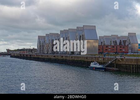 The Dunkirk Pilot Boat moored alongside the Quay of the Grand Harbour in front of distinctive newly built metal clad Apartments. Stock Photo