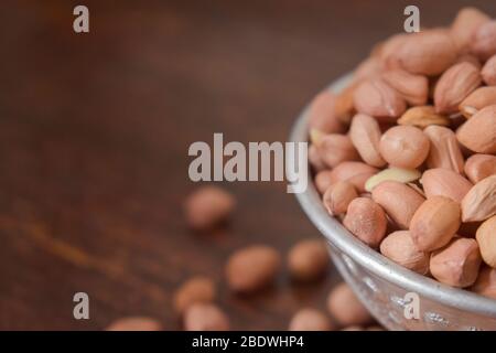 Peeled peanuts in a Silver bowl on wooden old Table. rustic style Stock Photo