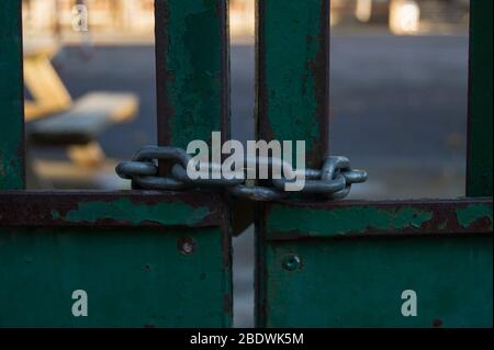 Iron chain closing a rusty metal door painted green. Stock Photo