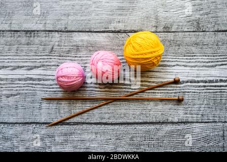 Flat lay of three colored wool balls, knitting needles laying on the wooden background. Stock Photo