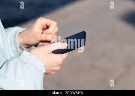 Female hands holding phone close-up on street with copy space Stock Photo