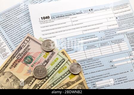 Some US dollar banknotes on the top of a U.S. Individual Income Tax Return form. Stock Photo