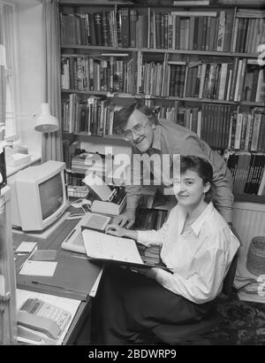 1987, historical, a couple working in a home office. In a compact book-lined study, technology seen on the desk... a computer of the day, keyboard and printer, and telephone. The introduction of the personal computer or PC at this time meant that working from home was far more possible than before. The year 1987 saw the release of the microsoft Windows 2 operating system which introduced a number of popular computing concepts, including windows, desktop icons and colour graphics. Stock Photo