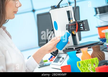 Young female designer works with a 3D printer in a design studio Stock Photo
