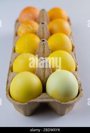 Different shades of yellow eggs in a paper container. Easter eggs. Stock Photo