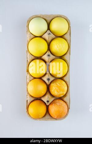 Different shades of yellow eggs in a paper container. Easter eggs. Stock Photo