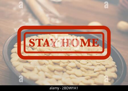 Stay home quarantine concept: traditional homemade apple pie on wooden table cooking for dining with red Stay home stamp above it. Cozy home mood Stock Photo