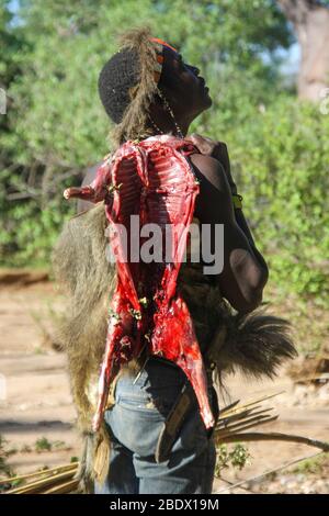 A Hadza hunter returns to the village with a his hunted prey. Photographed at Lake Eyasi, Tanzania Stock Photo