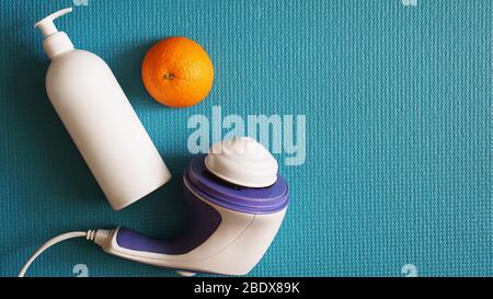 Electric massager for cellulite. Lotion, orange and anti-cellulite massage massager on a blue background Stock Photo