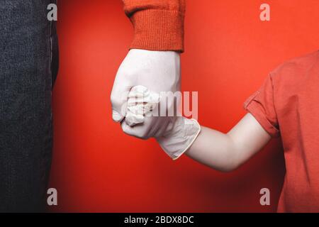Dad and son are holding hands in disposable medical gloves. Quarantine Concept Stock Photo