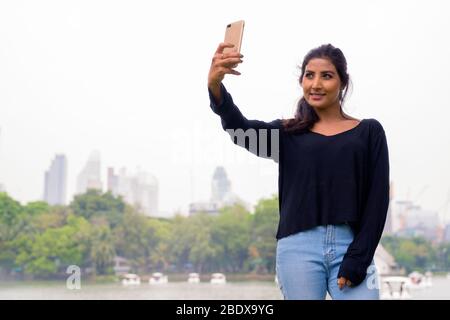Happy young beautiful Persian woman taking selfie at the park Stock Photo