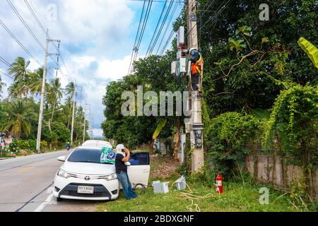 A professional electrician performs installation work on a pole. An electrician in professional equipment, working in dangerous conditions. Stock Photo