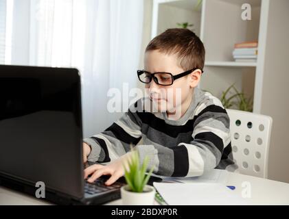 Online education and distance learning. Schoolboy studying at home with digital tablet and doing school homework. Training books and notebooks on tabl Stock Photo