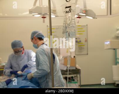 A saline drip in an NHS operating theatre as surgeons perform an operation. The NHS is under pressure as the Coronavirus drains resources. Stock Photo