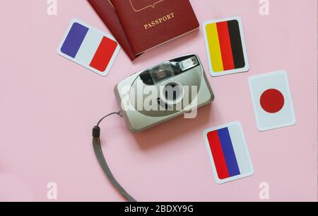 The camera, passports, flags of the countries of the world are depicted on a pink background from top to bottom Stock Photo
