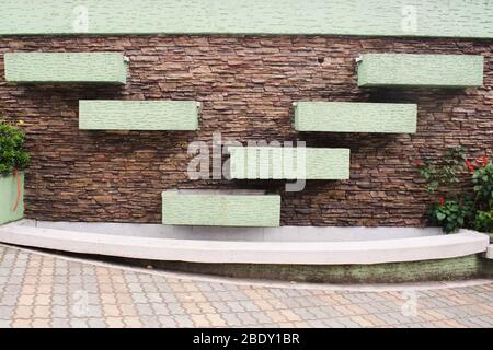 Brown brick wall with green painted rectangle arranged on a V pattern Stock Photo