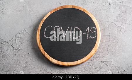 COVID-19 text on black board drawn by chalk. Gray background with covid message for title image. Stock Photo