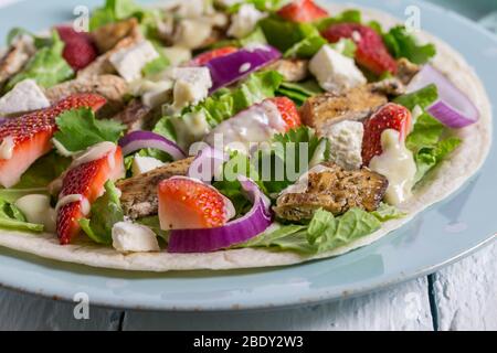 Open tortilla wrap with cold chicken salad, feta and strawberries - selective focus Stock Photo