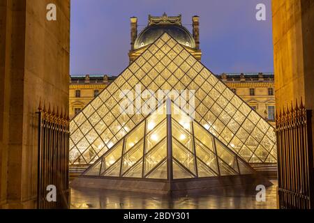 View of famous Louvre Museum with Louvre Pyramid at Night Stock Photo