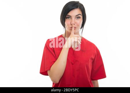 Portrait of attractive female nurse making silence gesture with index finger on white background with copy space advertising area Stock Photo