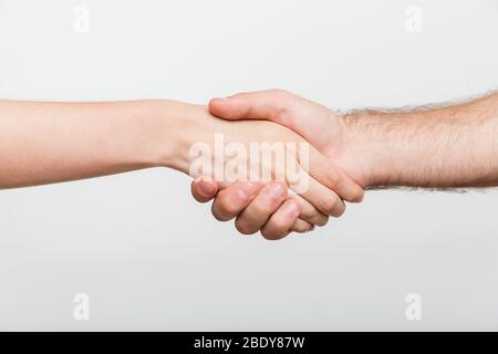 Closeup picture of a man and woman shaking hands isolated over white wall background. Stock Photo