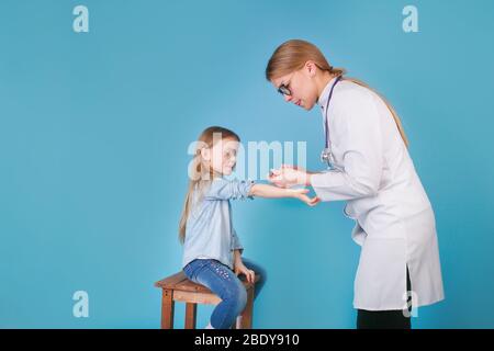 Young woman pediatrician performs a vaccination of a little girl. Stock Photo