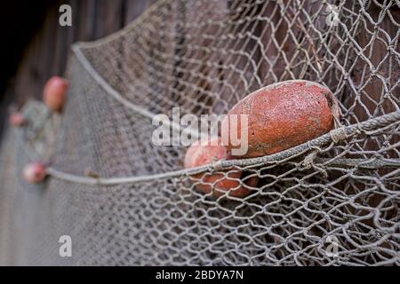 Colored old Fishing Net Floats on Worn Red wooden Wall Stock Photo