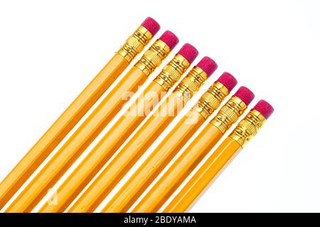 Horizontal close-up shot of the eraser ends of seven pencils laying on the diagonal.  Bottom left corner to upper right.  White background. Stock Photo