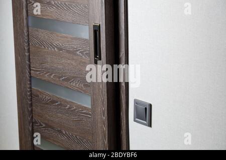 Two-key switch of gray color near the door, plastic mechanical switch. The light switch is installed after repair. Energy saving concept. Close up lig Stock Photo