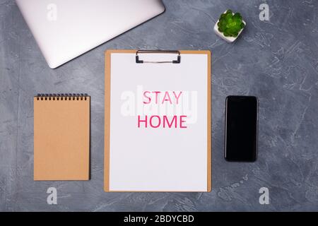 Motivation quote stay home to work from home during the spread of pandemic Covid-19 and Coronavirus on flat lay of modern workspace desk with laptop Stock Photo