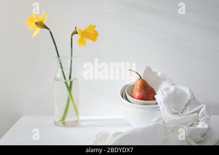 Still life with yellow-red pear Duchess in a pile of bowls and a white embroidered napkin on the white wall. Copy space Stock Photo