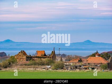 Ruined old stone pantile roofed farm buildings & view across Firth of Forth to Lomond Hills in Fife from East Lothian, Scotland, UK Stock Photo