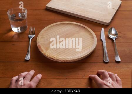 Point of view of a person about to eat on an empty wooden plate Stock Photo