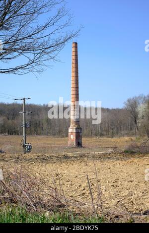 tall industrial chimney stack stands alone in the centre of an empty wasteland sole remnant of previous factory zala county hungary Stock Photo