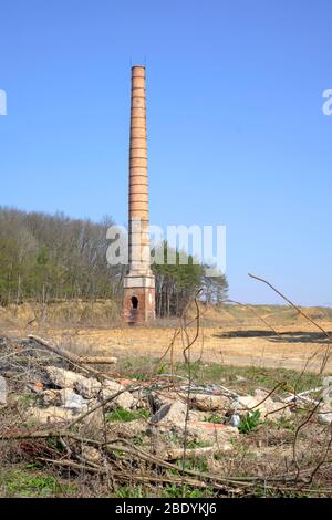 tall industrial chimney stack stands alone in the centre of an empty wasteland sole remnant of previous factory zala county hungary Stock Photo