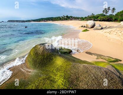 Moss covered rocks on the Palma Sola beach on the Pacific coast of Mexico. Stock Photo