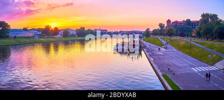 KRAKOW, POLAND - JUNE 12, 2018: Panorama of banks of Vistula river with Wawel Castle and walking people along promenades during twilights, on June 12 Stock Photo