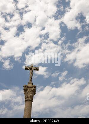 Jesus on an old stone cross against sky Stock Photo