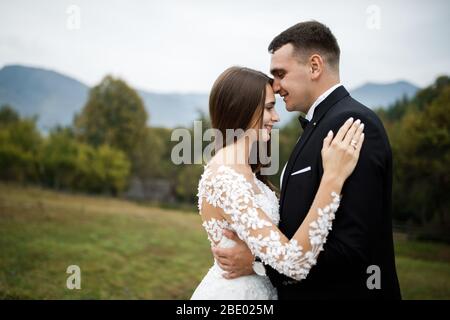 Stylish groom kissing gorgeous bride in sunset light, perfect moment, luxury ceremony at mountains with amazing view Stock Photo