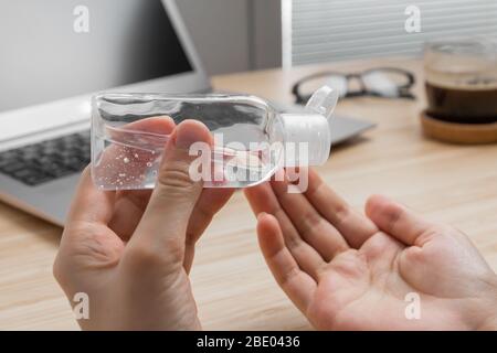 Closeup womans hand uses antibacterial gel to prevent coronavirus on her workplace. Hand sanitizer alcohol gel is pouring from a bottle on a Stock Photo