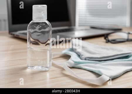 Hand sanitizer alcohol gel and protection mask are on the workspace for prevention of coronavirus. Health care during pandemic. Stock Photo