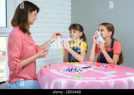 In the process of a board game, mom chooses a card from her daughter's hand Stock Photo