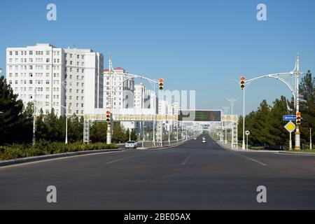 Ataturk Street with ornamented lamp posts, overhead road signs and traffic light. Ashgabat, Turkmenistan skyline with white marble buildings. Stock Photo