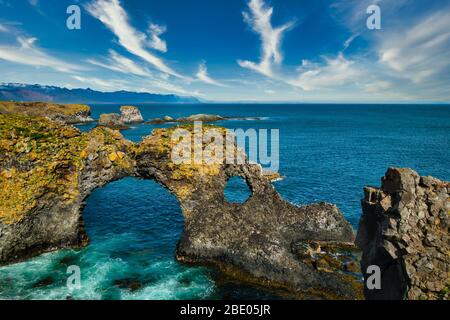 Gatklettur rock formations on Snaefellsnes peninsula and atlantic ocean on sunny day. Beautiful blue water and clear blue sky. No people visible, copy Stock Photo