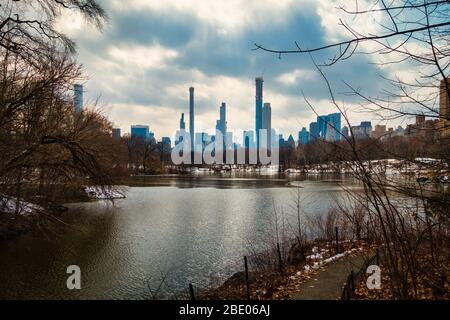 Lake in Central Park with Skyline of Manhattan in background. Dramatic, cloudy sky in New York City, NY. No people visible. Stock Photo