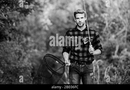 Fishing in my hobby. Handsome guy in checkered shirt with fishing equipment  nature background. Summer weekend concept. Hipster fisherman with rod  spinning net. Hope for nice fishing. Fishing day Stock Photo 