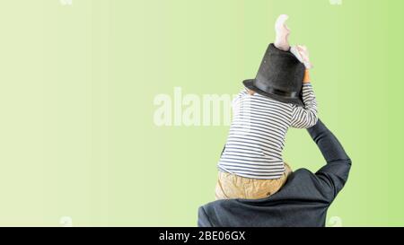 Conceptual photo of a man playing with his toddler son with rabbit ears at Easter Holidays at home during lockdown in Spain, Europe. Stock Photo