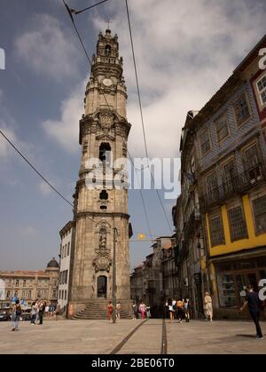 Tall bell tower of Torre dos Clérigos Church a Baroque church showing tram lines and street life Porto Portugal Stock Photo